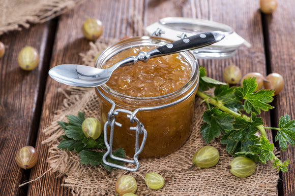 Gooseberry Jam with Gooseberries scattered around the jar.